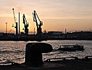 011_25894 | Abenddmmerung an der Elbe; Eisenpoller am Kai, eine Barkasse der Hafenrundfahrt fhrt an ihren Liegeplatz - im Hintergrund der rotgefrbte Abendhimmel und die Silhouetten der Krne.