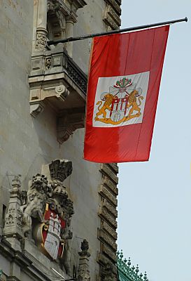 011_25904 | die Hamburger Staatsflagge am Rathaus, darunter das Wappen der Freien und Hansestadt Hamburg mit der stilisierten Burg.