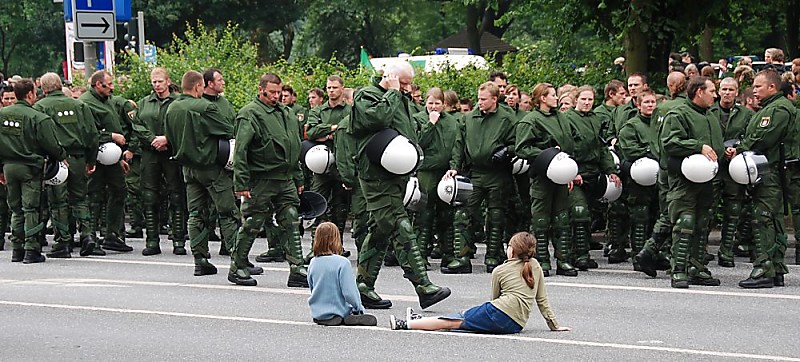 011_25936 | ddie Einsatzkrfte der Hamburger Polizei sammeln sich bei der Protestdemonstration gegen den Asem Gipfel / Konferenz in der Hansestadt Hamburg - die Polizisten stehen an der Strasse mit ihrem Helm in der Hand, ein Einsatzleiter wird von Kindern beobachtet.