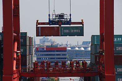011_25943 |  zwei Standartcontainer  hngen an den Haken der Laufkatze der Containerbrcke - im Hintergrund ein Verwaltungsgebude der HHLA am Burchardkai und die Silhouette von der Hansestadt Hamburg.