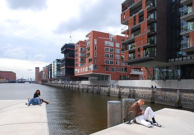 011_25976 |  die neue Architektur der Hafencity; Blick von den Magellan Terrassen - Hamburg Touristen sitzen am Rand des Hafenbeckens vom Sandtorhafen. Im Hintergrund die Sandtorhafenklappbrcke und links der Kaispeicher A die zuknftigen Elbphilharmonie, dem neuen Wahrzeichen der Hansestadt Hamburg.  
