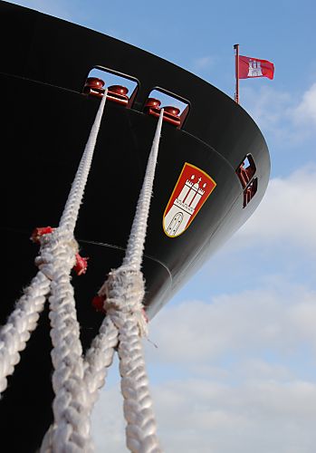 011_25990 | Kstarke Trossen halten das Contaienrschiff "Hanover" am Kai; am Bug trgt das neue Frachtschiff das Hamburger Wappen - eine Hamburg Flagge weht im Wind.
