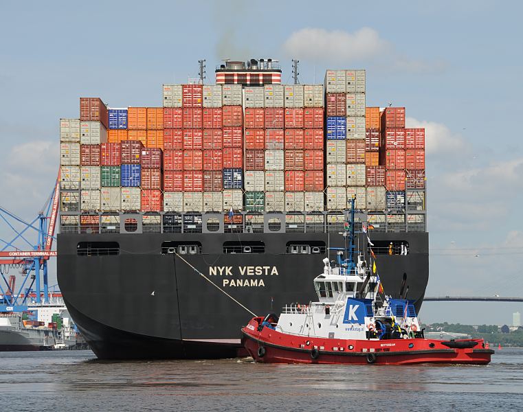 89-8029 |  Das Containerschiff NYK Vesta ist hoch mit Containern beladen - ein Hafenschlepper untersttzt den Frachter bei der Ausfahrt aus dem Hamburger Hafen. Die NYK VESTA hat eine Breite von 45,60m und eine Lnge von 338m. Mit 8600 TEU voll beladen hat das Frachtschiff einen Tiefgang von 14,50m und kann bei einer Maschinenleistung von ca. 87000 PS 24,5 kn fahren. www.fotograf-hamburg.de
