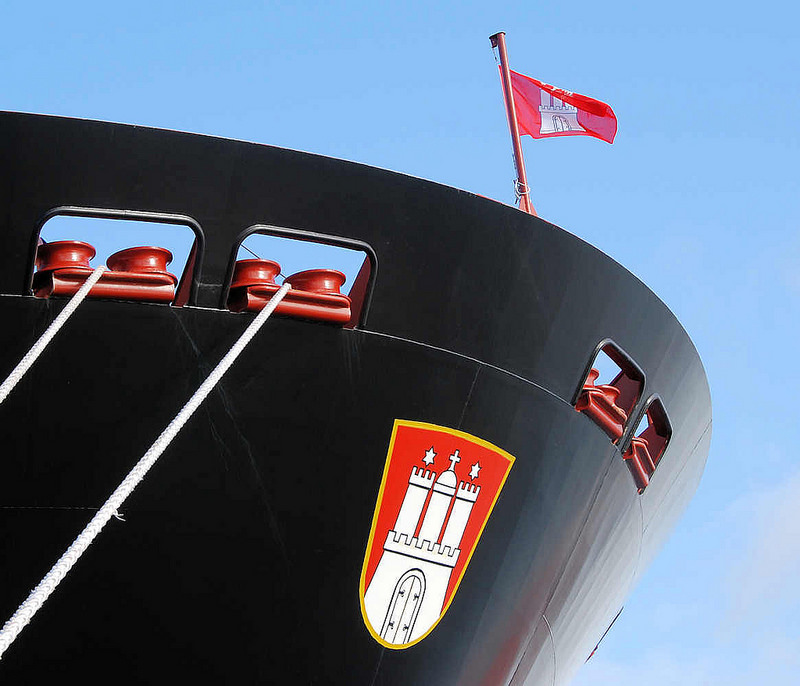 2120 011_15820 Seil und Schiffsbug des Containerschiffs "Hanover" am Hamburger Container Terminal Altenwerder; ber dem Hamburg Wappen flattert die Hamburg Fahne im Wind.