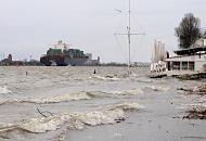 3656_0734 Wellen schlagen auf den Strand bei Hochwasser an der Strandperle in Hamburg Oevelgnne; die Sonnenschirme sind zusammengefaltet, Tische und Sthle gesichert. Ein Containerschiff verlsst den Hamburger Hafen, es wird mit Hilfe von Schleppern in die Fahrrinne gebracht.