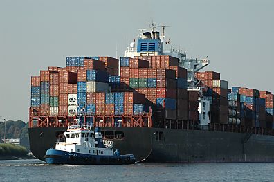 011_25839 |  ein Schlepper dirigiert das Heck eines Frachtschiffs auf der Elbe - die Container sind hoch auf dem Heck vom Containerschiff gestapelt .