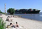 011_25831 | Badegste sonnen sich im Sand an der Elbe; ein Containerschiff verlsst hoch beladen Hamburg und fhrt Richtung Nordsee.