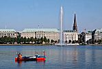 011_25826 | ein Kanu treibt auf der Binnenalster; die Alsterfontaine sprudelt in den blauen Hamburg Himmel; im Hintergrund die historische Architektur am Ballindamm und der Kirchturm der St. Jakobikirche.