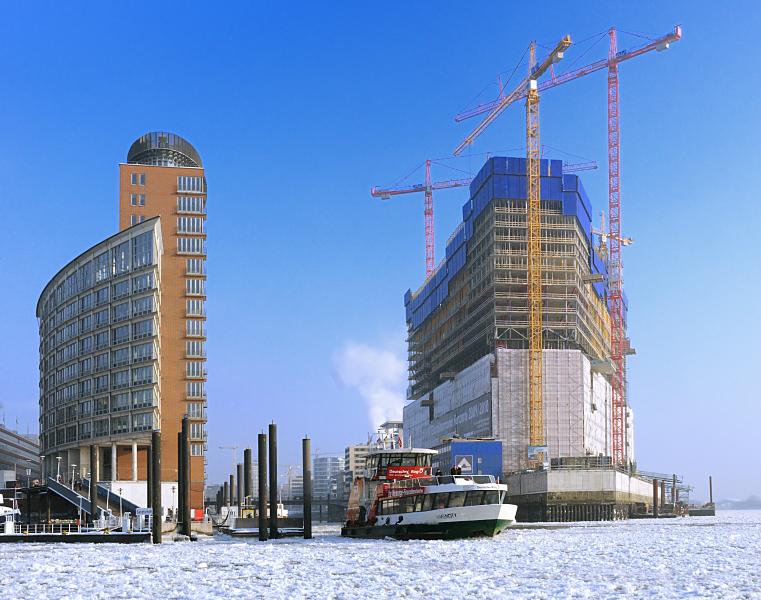 Hamburg-Aufnahmen im Winter; Baustelle der Elbphilharmonie, Treibeis auf der Elbe. 110_5304 |Baukrne ragen an der Baustelle der zuknftigen Elbphilharmonie in den blauen Winterhimmel. Eine Hafenfhre legt gerade vom Anleger Sandtor ab und fhrt durch das dichte Treibeis Richtung Landungsbrcken. www.fotograf-hamburg.de