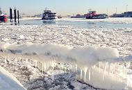 111_5688 | Ein Schiffstau ist am Anleger Oevelgnne mit dicken Eis und Eiszapfen bedeckt. In der Hamburger Wintersonne fahren Elbfhren durch das Treibeis Richtung Finkenwerder. Im Hintergrund liegt die Mndung des Khlbrandfleets / Sderelbe in die Elbe.