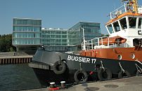 011_26030 | Der Schlepper BUGSIER 17 hat am Anleger in Hamburg Neumhlen fest gemacht; die dicken Tampen sind um die eisernen Poller am Steg gelegt. Gummireifen dienen als Fender und sollen den Stoss beim Anlegen abfedern. Im Hintergrund die moderne Architektur am Elbufer von Hamburg Neumhlen.  www.christoph-bellin.de