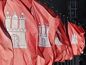 011_26038 |  Die Hamburger Landesflaggen wehen Wind - auf rotem Grund steht das Hamburger Wappenzeichen die Burg mit drei Trmen, Burgzinnen und geschlossenem Burgtor. Der mittlere Turm mit dem Kreuz auf der Turmspitze symbolisiert den mittelalterlichen Hamburger Dom, die beiden Trme mit den Sternen ber den Turmzinnen sind Mariensterne, die an die Schutzpatroninnen der Stadt, Maria, erinnern sollen.   www.christoph-bellin.de