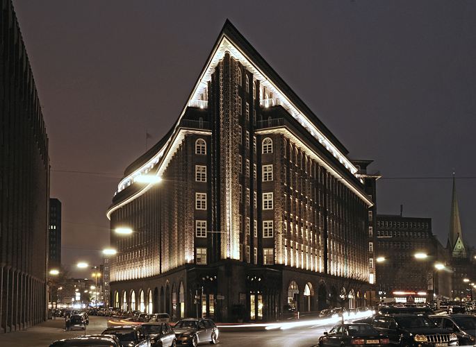 41_656546 |  Hamburg bei Nacht - Nachtaufnahme der Hamburger Sehenswrdigkeiten; das beleuchtete Chilehaus im Kontorhausviertel Hamburgs. Das expressionistische Brogebude wurde 1922 - 1924 in der Hamburger Innenstadt / Altstadt errichtet; der Architekt war  Fritz Hger; die Spitze des 10 stckigen Gebudes soll an einen Schiffsbug erinnernn. Rechts im Hintergrund die St. Petrikirche, eine der fnf Hauptkirchen Hamburgs.  www.fotograf-hamburg.de