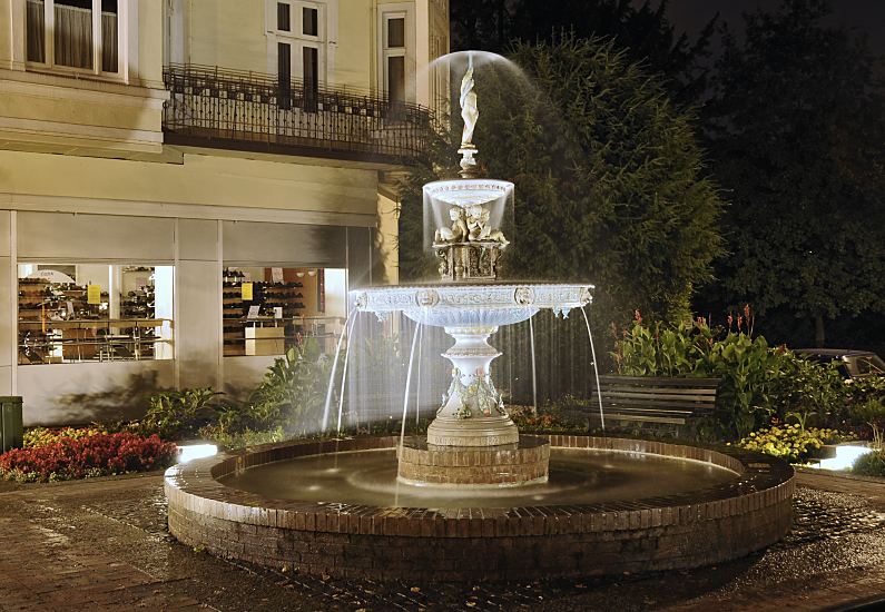 95-21505 |Fotos aus dem Hamburger Bezirk Bergedorf - Nachtaufnahme Springbrunnen. Der gusseiserne Brunnen am Bergedorfer Kaiser Wilhelm Platz wird nach seinem Spender Carl Sievers auch Sievers Brunnen genannt. Die Anlage wurde 1888 von Sievers gestiftet; er damals war der Besitzer der Bergedorfer Wasserwerke, die sich bis 1899 in privatem Eigentum befanden.  Auf seiner Spitze steht eine Putte von der aus das Wasser schirmfrmig nach unten fllt -  vier weitere Knaben sitzen unter dem kleinen Wasserbecken www.fotograf- hamburg.de