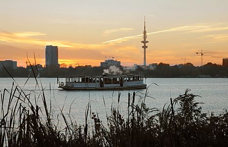 011_25946 | der historische Alsterdampfer St. Georg auf der Hamburger Aussenalster - im Vordergrund Schilf am Alterufer, im Hintergrund das Hamburgpanorama mit dem Telemichel im Sonnenuntergang.